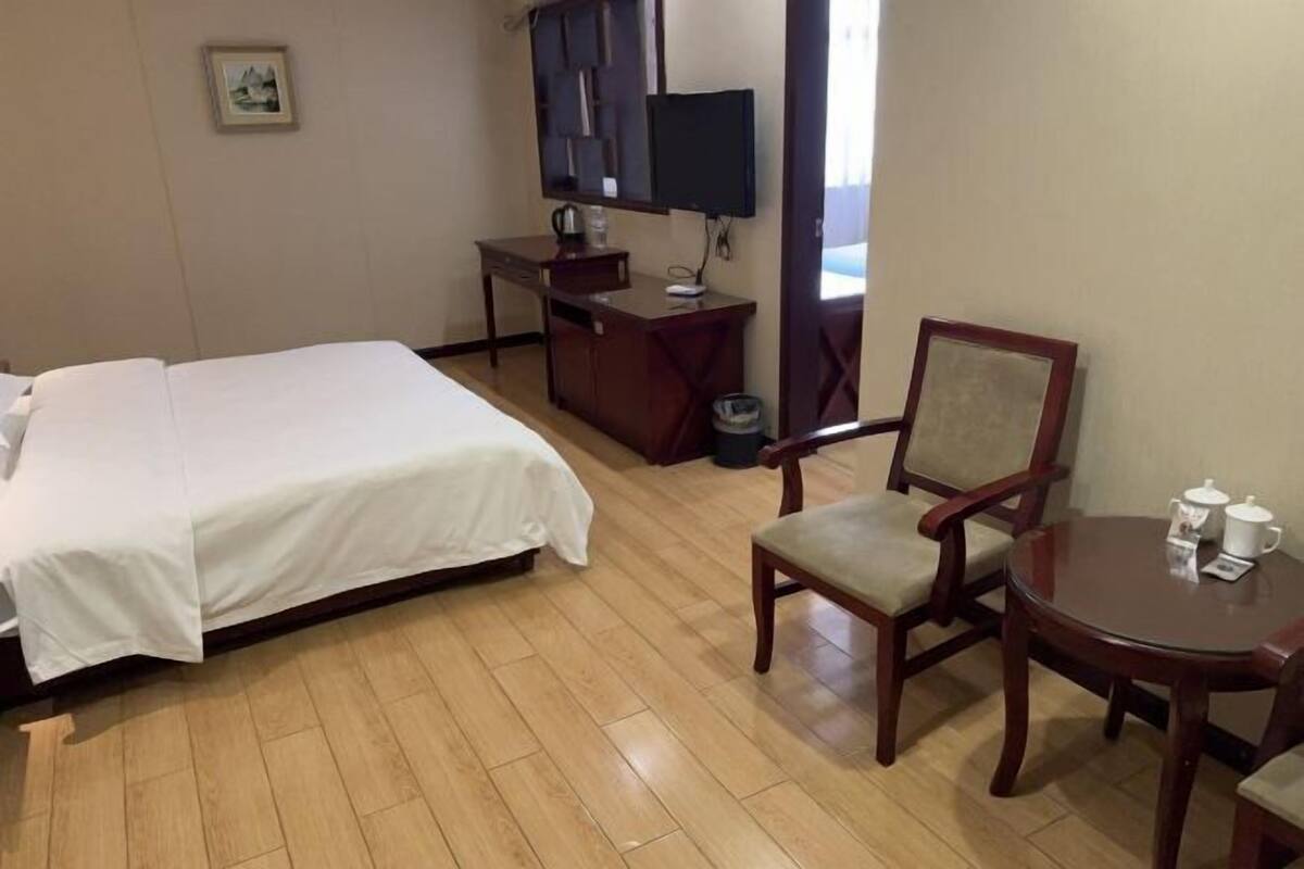 Hotelkamer met een bed, een bureau, een stoel, een televisie en een klein tafeltje met een kopje en schotel.