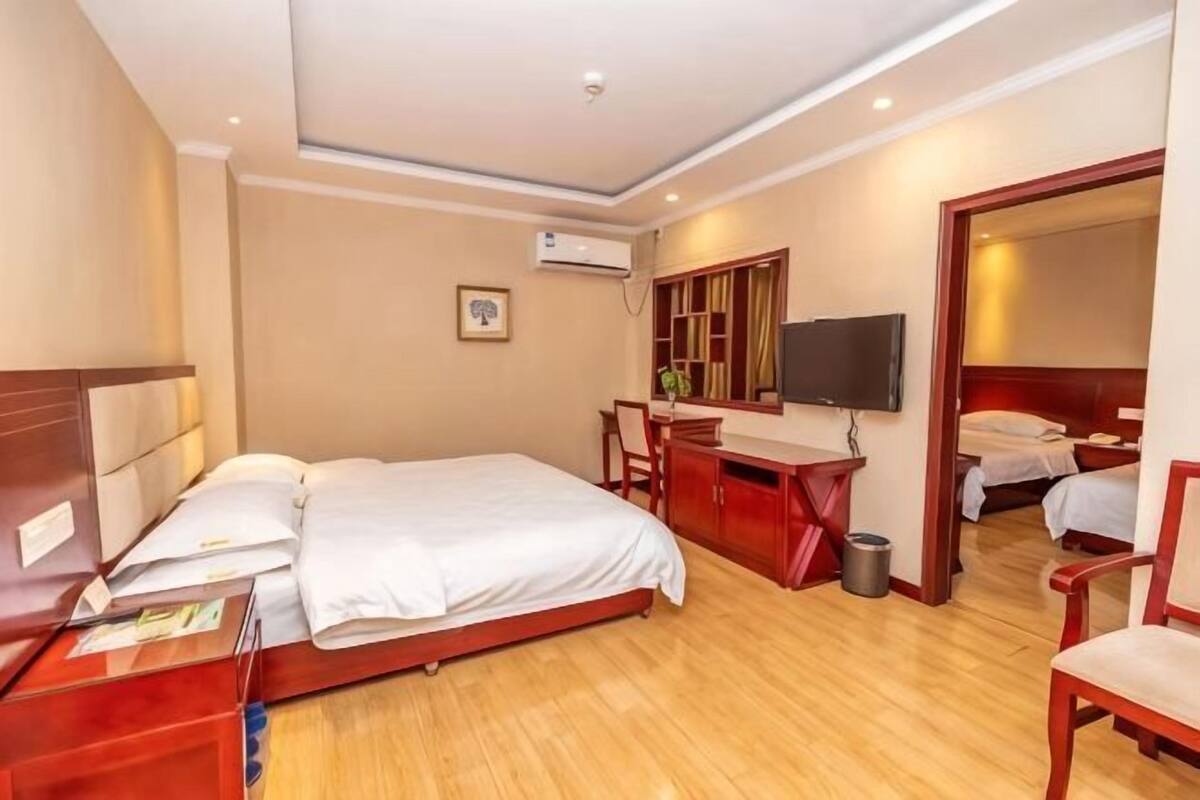 Een hotelkamer met een bed, bureau, stoel, televisie en een kleine badkamer.