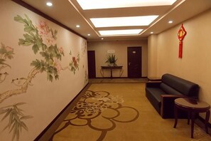 Een hotel lobby met een bank, een bijzettafeltje en een decoratieve wand.