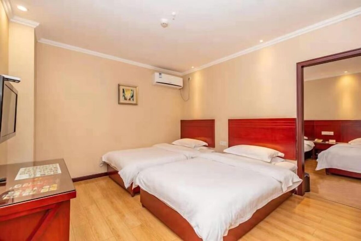 Una habitación de hotel con dos camas, piso de madera, un escritorio con ordenador y un espejo.