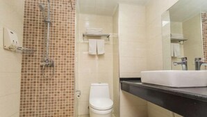 Een badkamer met douche, toilet, wastafel en spiegel.