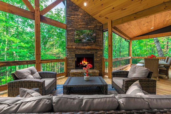 A cozy outdoor seating area with wicker furniture and a stone fireplace.