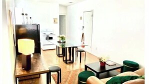 Una sala de estar moderna con un sofá de cuero marrón, una mesa de comedor con sillas, una mesa de centro y una lámpara.