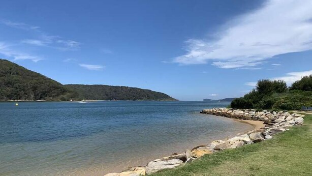 A clear view of a lake with a rocky shoreline and distant hills. - Stroll to beach, cafes & restaurants (BOOKER BAY)