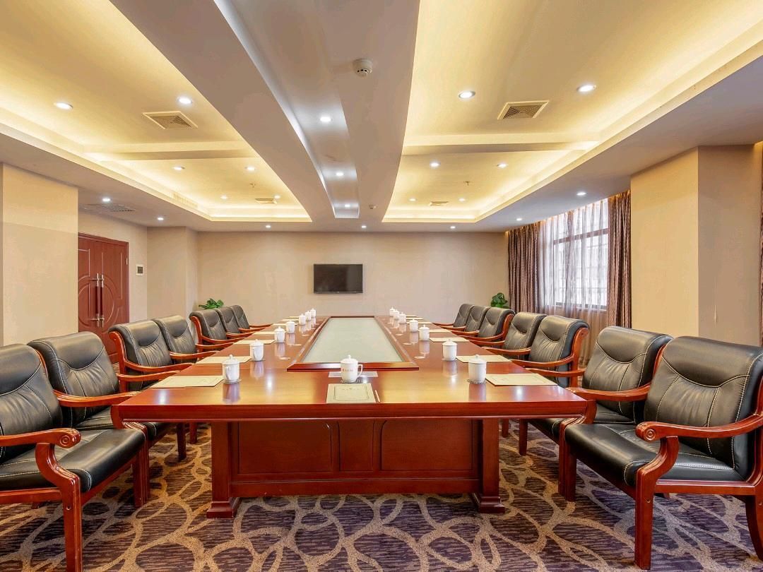 A conference room with a long table, multiple chairs, and a carpeted floor.