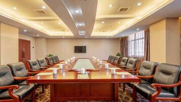 A conference room with a long table, multiple chairs, and a carpeted floor.
