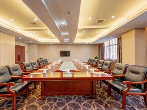 A conference room with a long table, multiple chairs, and a carpeted floor. - Tiancheng Hotel (Yuanjiang)