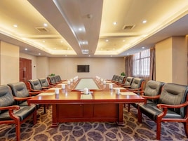 Un salón de conferencias con una larga mesa, varias sillas y piso alfombrado.