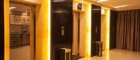 A hotel corridor with elevator doors, a number sign, and a trash bin.