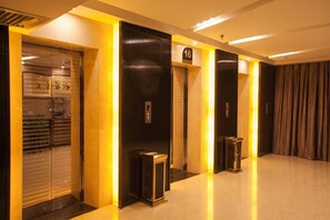 A hotel corridor with elevator doors, a number sign, and a trash bin. - Tiancheng Hotel (Yuanjiang)