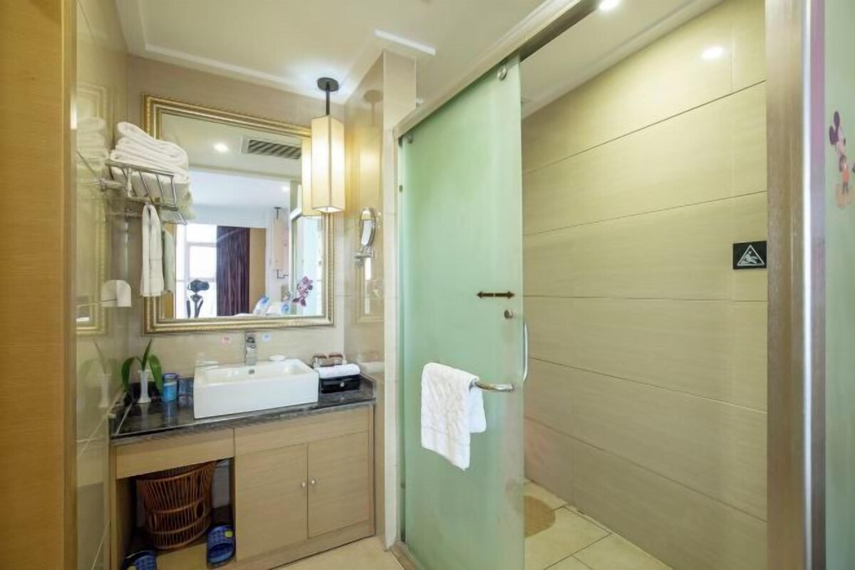 A bathroom with a sink, mirror, towel rack, and a glass shower enclosure.