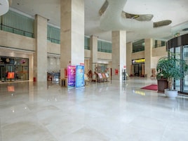 Um hall amplo com pé-direito alto, grandes colunas e uma planta central.