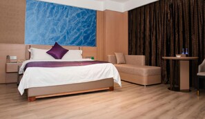 A hotel room with a bed, a sofa, a small table, and a large window with curtains. - Tiancheng Hotel (Yuanjiang)