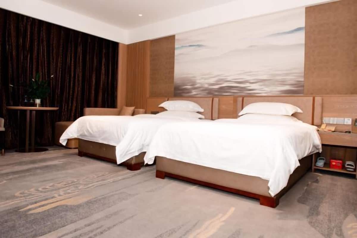 A hotel room with two beds, a large abstract painting on the wall, and a wooden floor.