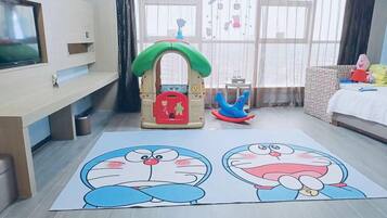 A room with a play area, a television, and a window with curtains.