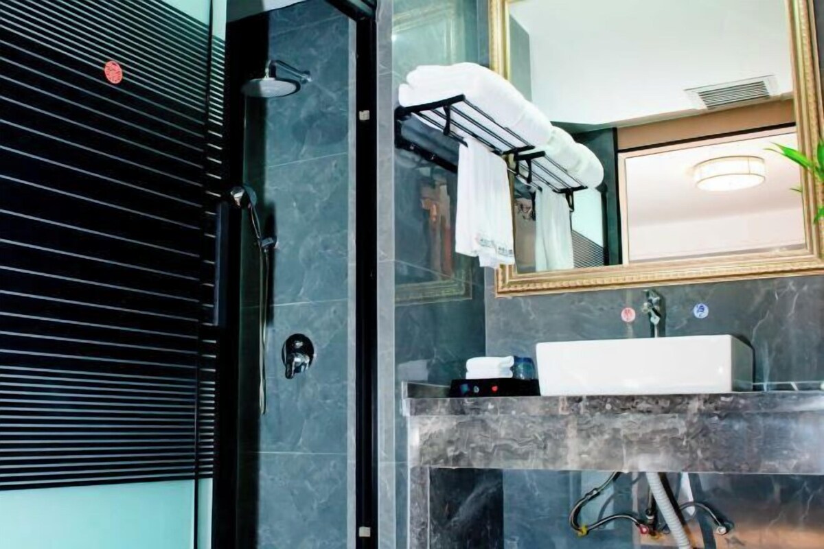 A modern bathroom with a glass shower enclosure, a marble sink, and a mirror with a towel rack.