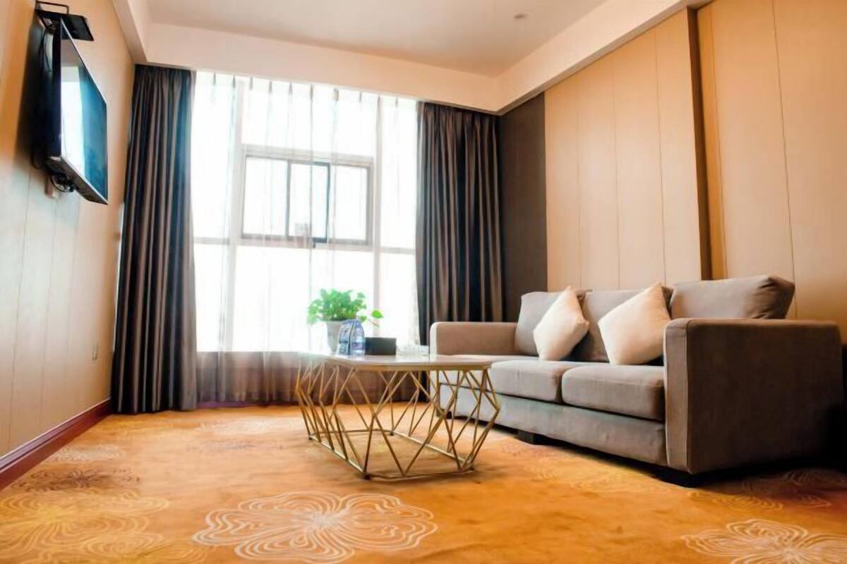 A living room with a sofa, a coffee table, and a TV mounted on the wall.