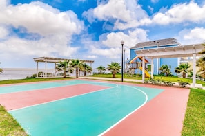 A basketball court with a view of the ocean and a building with a blue roof. - Beautiful home with oceanview, pool, hot tub, central AC, & washer/dryer (Port Isabel)