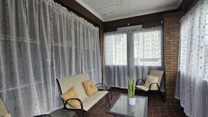 Una habitación acogedora con un sofá, sillones, una mesita y una planta en maceta.