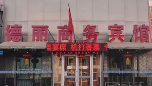 Un hôtel avec une enseigne en caractères chinois et une banderole rouge annonçant une offre spéciale.
