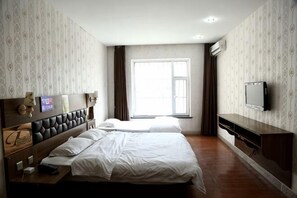 Een hotelkamer met twee bedden, een televisie, een bureau en een raam met gordijnen.