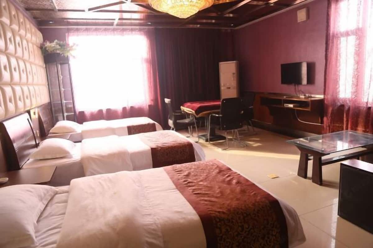 A hotel room with two beds, a desk, a chair, a television, and a window with curtains.