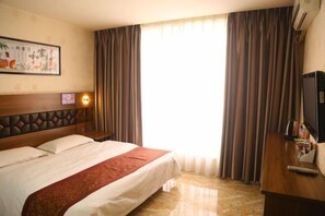 A hotel room with a bed, a desk, a TV, and curtains.