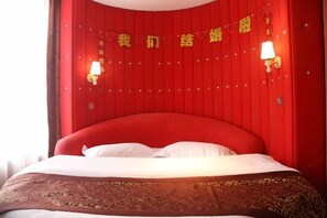 Ein rotes, gepolstertes Bett mit weißen Kissen und einer gemusterten Tagesdecke.