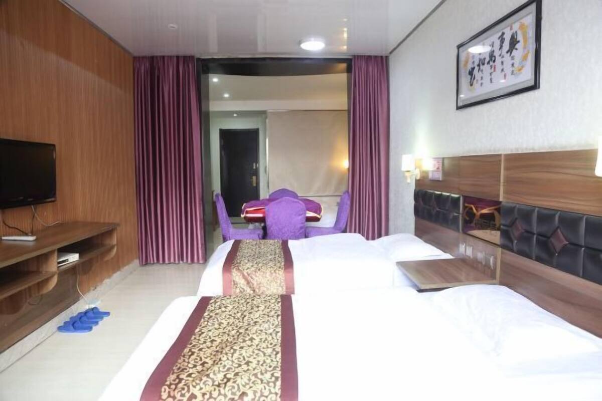 A hotel room with a large bed, a TV, a desk, and a chair.