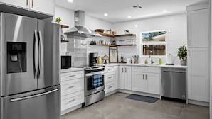 Una cocina moderna con armarios blancos, electrodomésticos de acero inoxidable y horno empotrado.