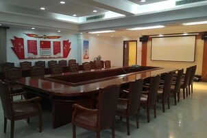 Un salón de conferencias con una larga mesa y sillas, una pantalla de proyector y una pared con carteles informativos.