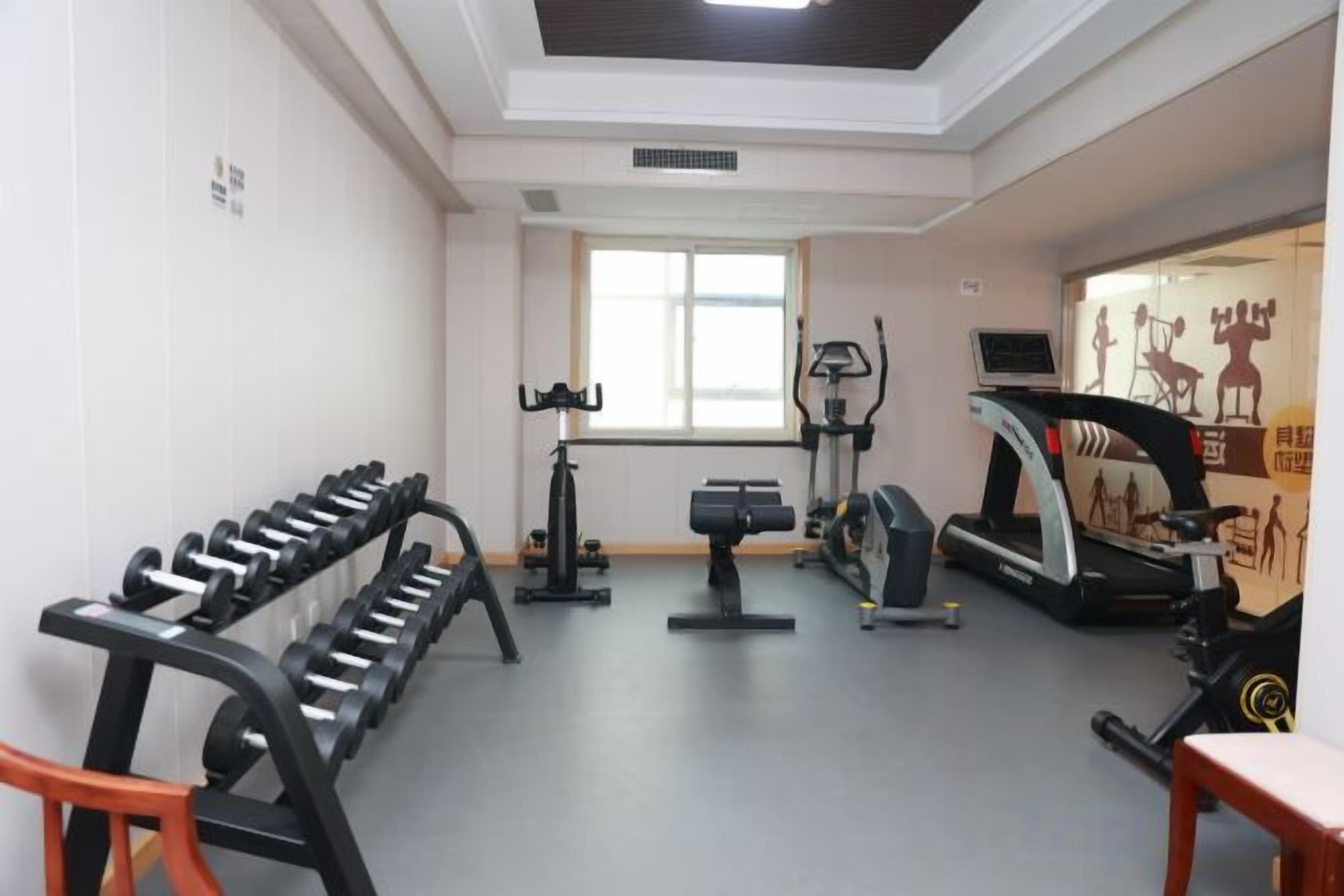 Un gimnasio con equipo de ejercicio, cinta de correr y ventana.