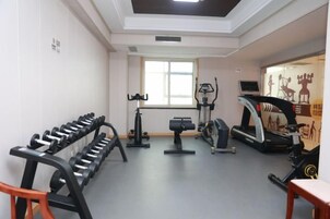 Un gimnasio con equipo de ejercicio, cinta de correr y ventana.