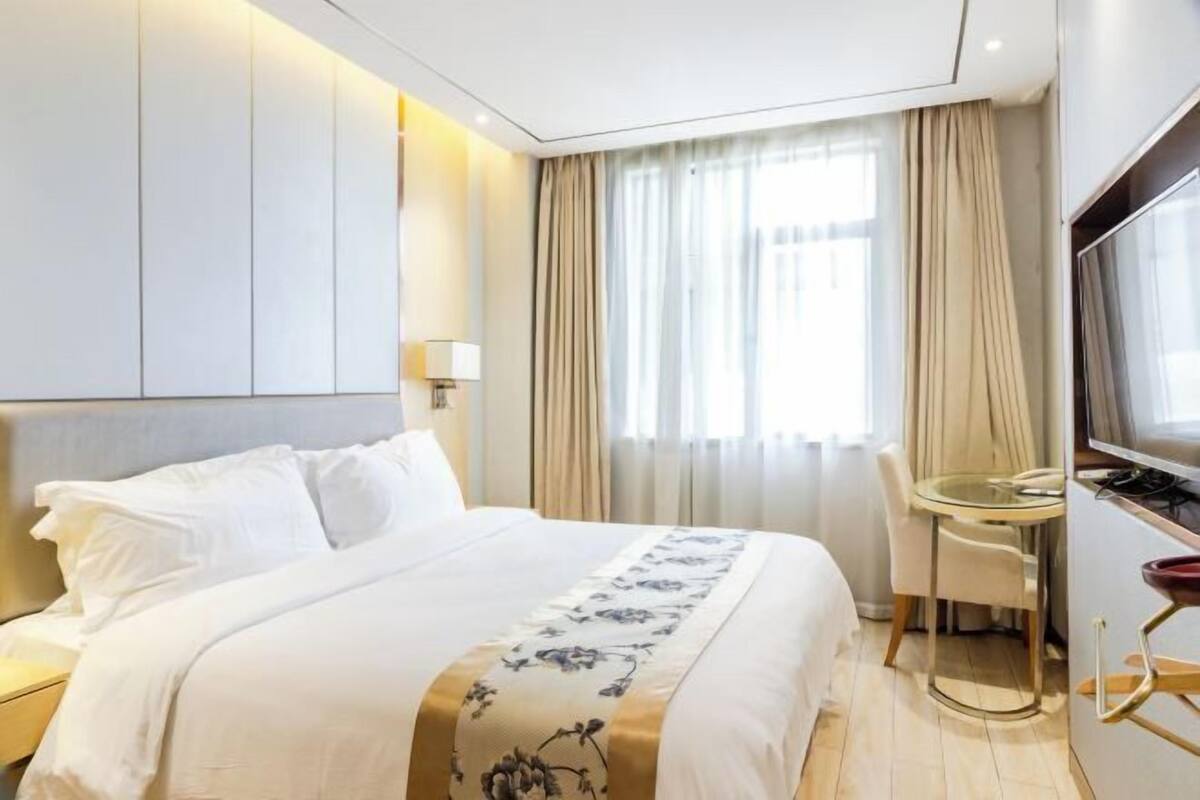 Hotellihuone, jossa on sänky, työpöytä, tuoli ja televisio.