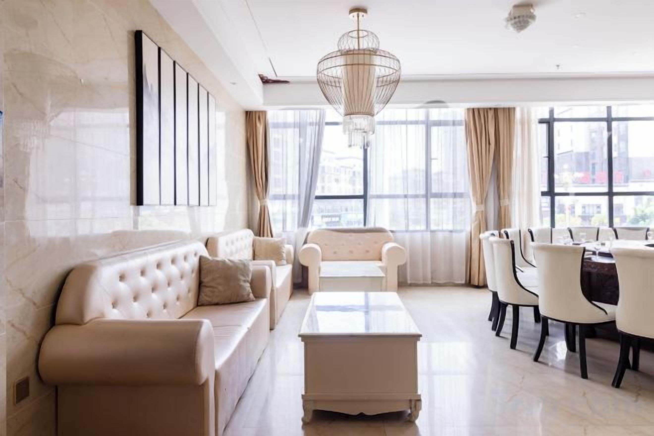 A modern living room with a sofa, armchairs, a coffee table, and a dining area with chairs and a table.