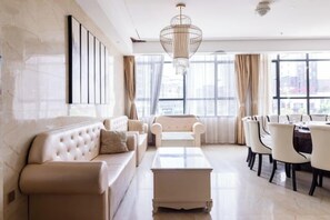 A modern living room with a sofa, armchairs, a coffee table, and a dining area with chairs and a table. - Yitian Hotel Jinxi (Jinxi)