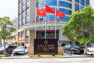 Entrada de un hotel con un letrero que dice "Yi Tian Hotel" y varias banderas rojas.