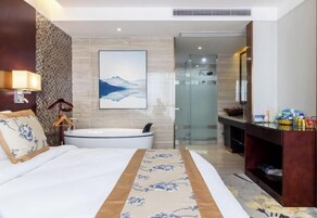Habitación de hotel con cama, bañera, ducha, armario de madera y un cuadro en la pared.