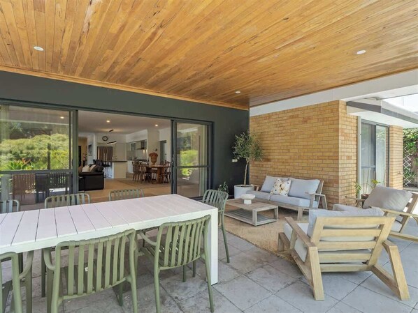 An outdoor patio with a dining table and chairs, a sofa, and a brick wall.