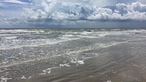 Ein Strand mit Wellen und einem bewölkten Himmel.