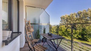A balcony with a wooden chair, a small table, and a patterned rug. - Bright Apartment with Balcony | Workspace (Kolobrzeg)