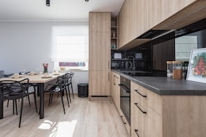 Una cocina moderna con armarios de madera, encimera negra y un área de comedor con sillas negras.