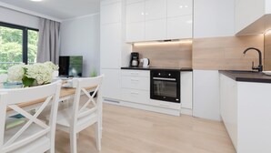 Una cocina moderna con armarios blancos, horno empotrado y cafetera.