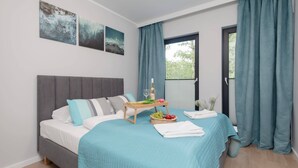 Un dormitorio con una cama, una mesita de noche con una botella, vasos y una cesta de frutas.