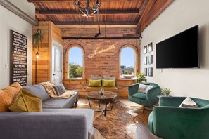 Una sala de estar acogedora con chimenea de ladrillo, un televisor grande y asientos cómodos.