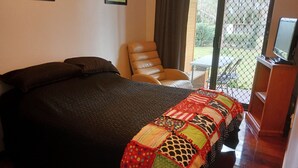 Quarto com cama, poltrona e televisão.