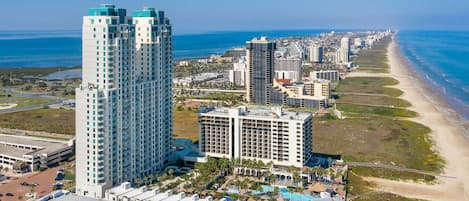 Un hotel de gran altura con varias plantas, piscina y vista al mar.