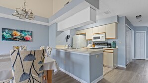 A modern kitchen with a central island, a dining area with a table and chairs, and a living space with a sofa.