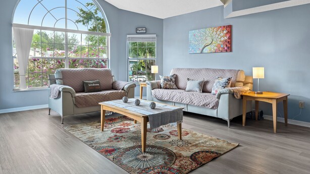 A spacious living room with a large window, two sofas, a coffee table, and a rug.
