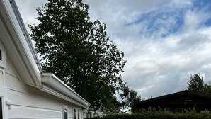 Eine überdachte Terrasse mit Tisch und Sitzgelegenheiten neben einem weißen Gebäude mit Fenster und Tür.